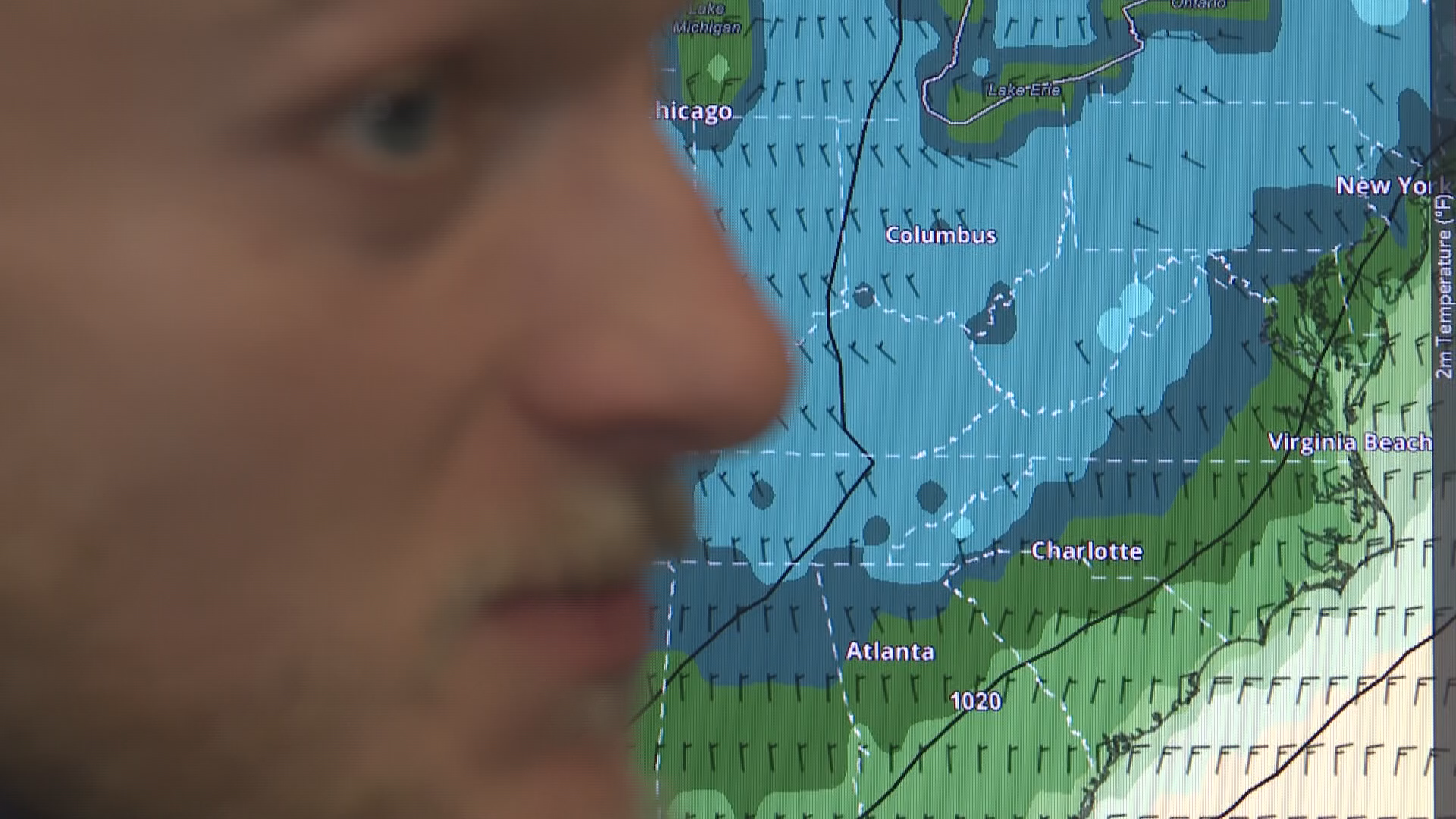 A man stands in front of a weather map
