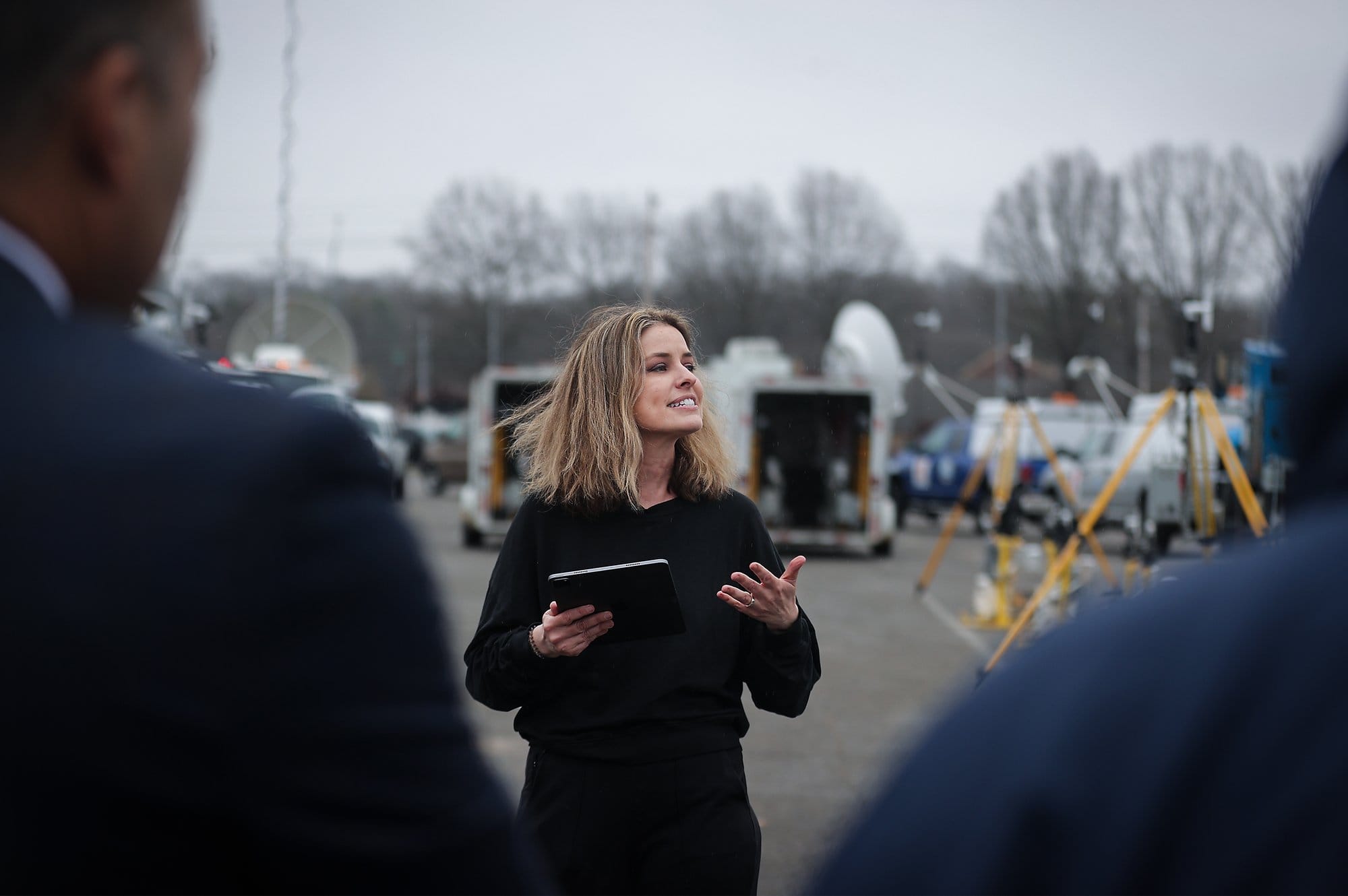A researcher speaks to attendees while holding a tablet at an outdoor event showcasing weather instruments used to study tornadoes in the southeastern United States.