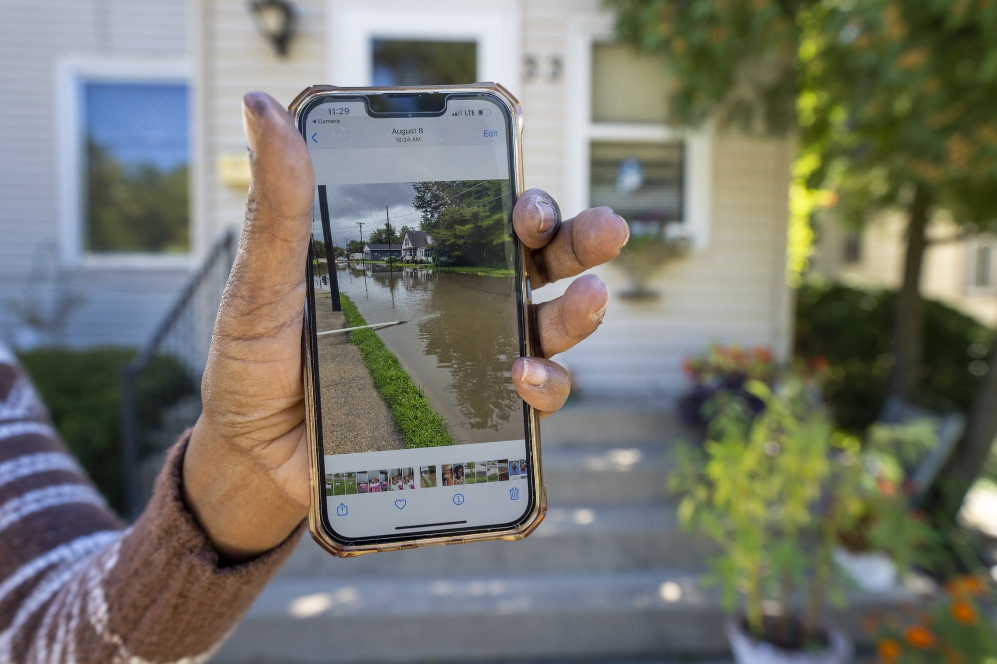 Laurie Thomas displays a photo she made of flooding that occurred earlier this year. The picture shows floodwaters covering the entire street.