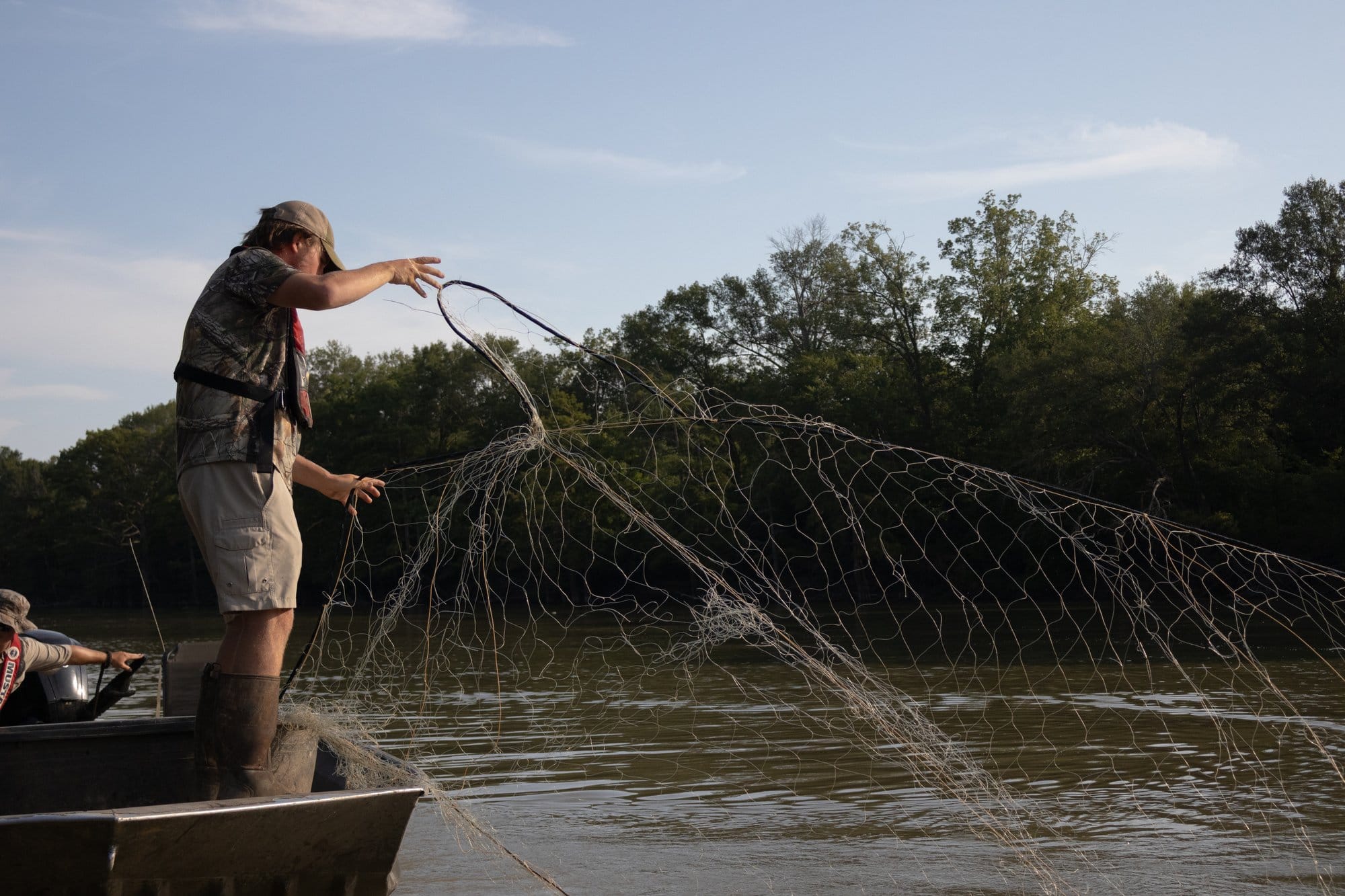 Ethan Chism casts a net into the water.