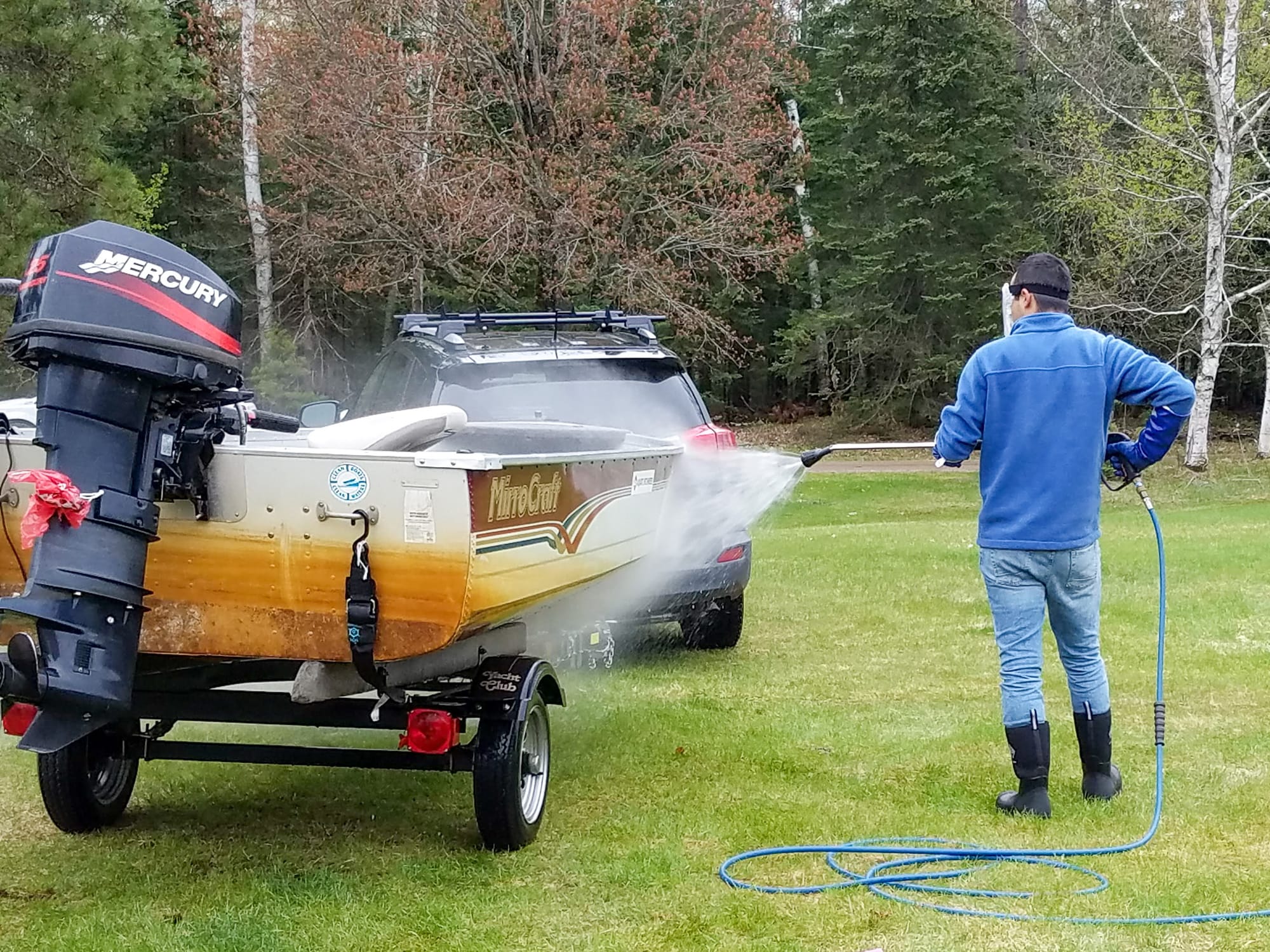 A man power washes a boat on a trailer.