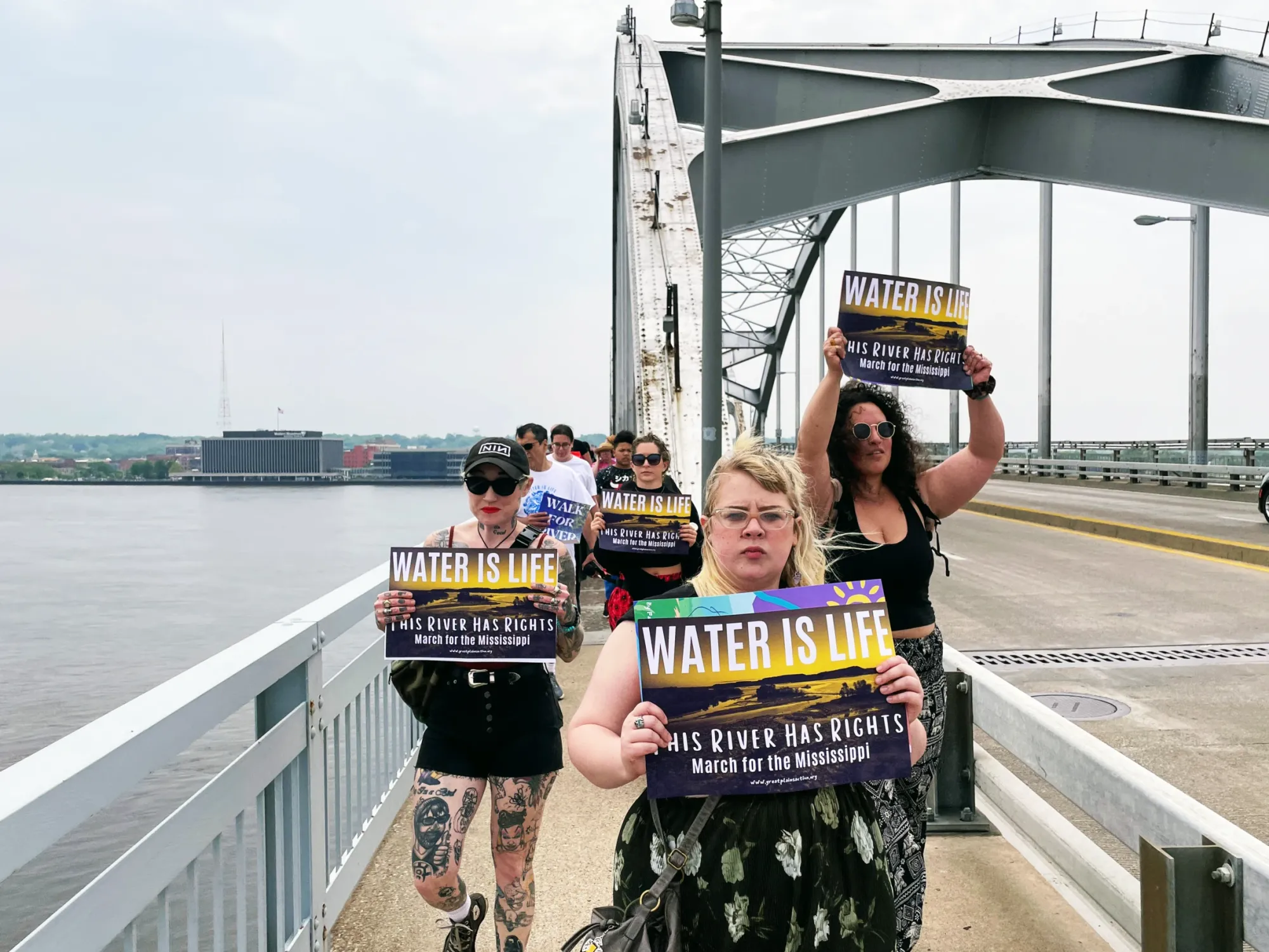 Advocates with loudspeaker and posters in-hand march over the Centennial Bridge.