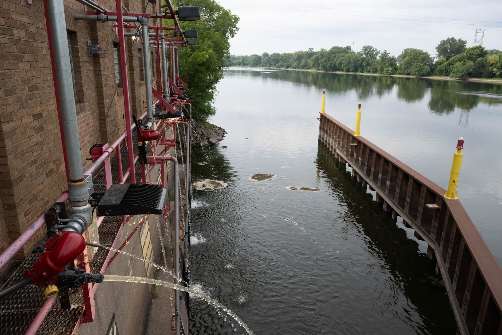 Small jets of water can be seen flowing back into the river outside a brick facility.
