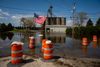 A parking lot is flooded, with hazard cones throughout