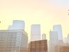 The sky surrounding skyscrapers is hazy and filled with smoke
