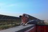 A man in a ballcap leans against a truckbed with rows of solar panels behind him
