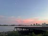 The Moon hangs high over the Mississippi River, a bridge and downtown New Orleans at sunset