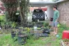 Man stands beside rose of potted plants at an urban farm in Abbeville, Louisiana.