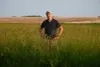 A farmer stands among tall crops in a field in Livingston County, Missouri.