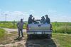 Farmers sit in the back of a truck