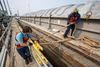 Two men work to secure a barge in place with rope 