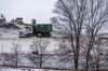 A dump truck carries industrial waste through a snow-covered landfill.