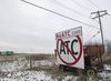 An old piece of farm equipment sits idle near a highway with a sign attached to it that reads NoATC.com, and a graphic in large font below, ATC crossed out