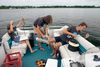 Three people work with various equipment on a small boat in the water