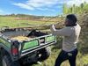 A man loads woody material into the back of a farm utility vehicle