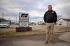 A man in a black sweatshirt stands in front of a Farm Bureau sign 