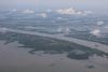 Aerial view of a gulf landscape, sparse land intermixed with streams and water bodies. A ship moves through one of the main channels