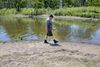 A man walks on a sandy shore next to a shallow body of water