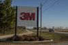 A truck drives past a large 3M sign beside a highway 