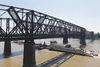 An industrial ship moves under a long bridge