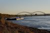 A barge travels along the Mississippi River near Mud Island in Memphis, with the Hernando de Soto Bridge spanning the river in the background.