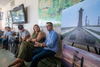 Five people sit at the front of a room and address a crowd. Big SpaceX images, including photos of the Starship rocket and maps of planned development, are next to them.