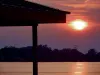 An image of a setting sun by a cabin. 