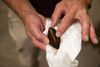 A man's hands hold a brown mussel.