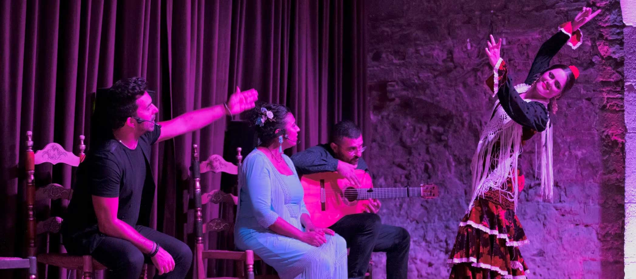 Flamenco performers on stage with instruments and a dancing woman in a dress.