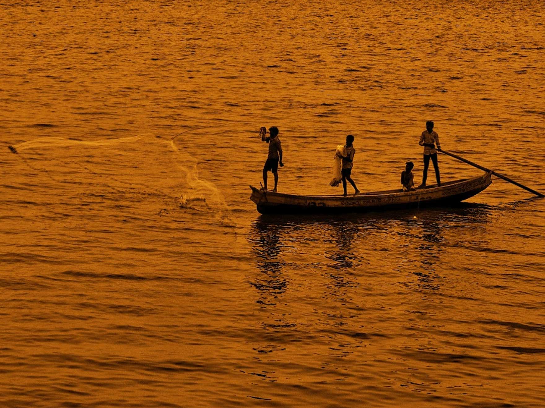 Fishermen&nbsp;casting their nets in the twilight glow of the Godavari River, with the bridge elegantly silhouetted in the background