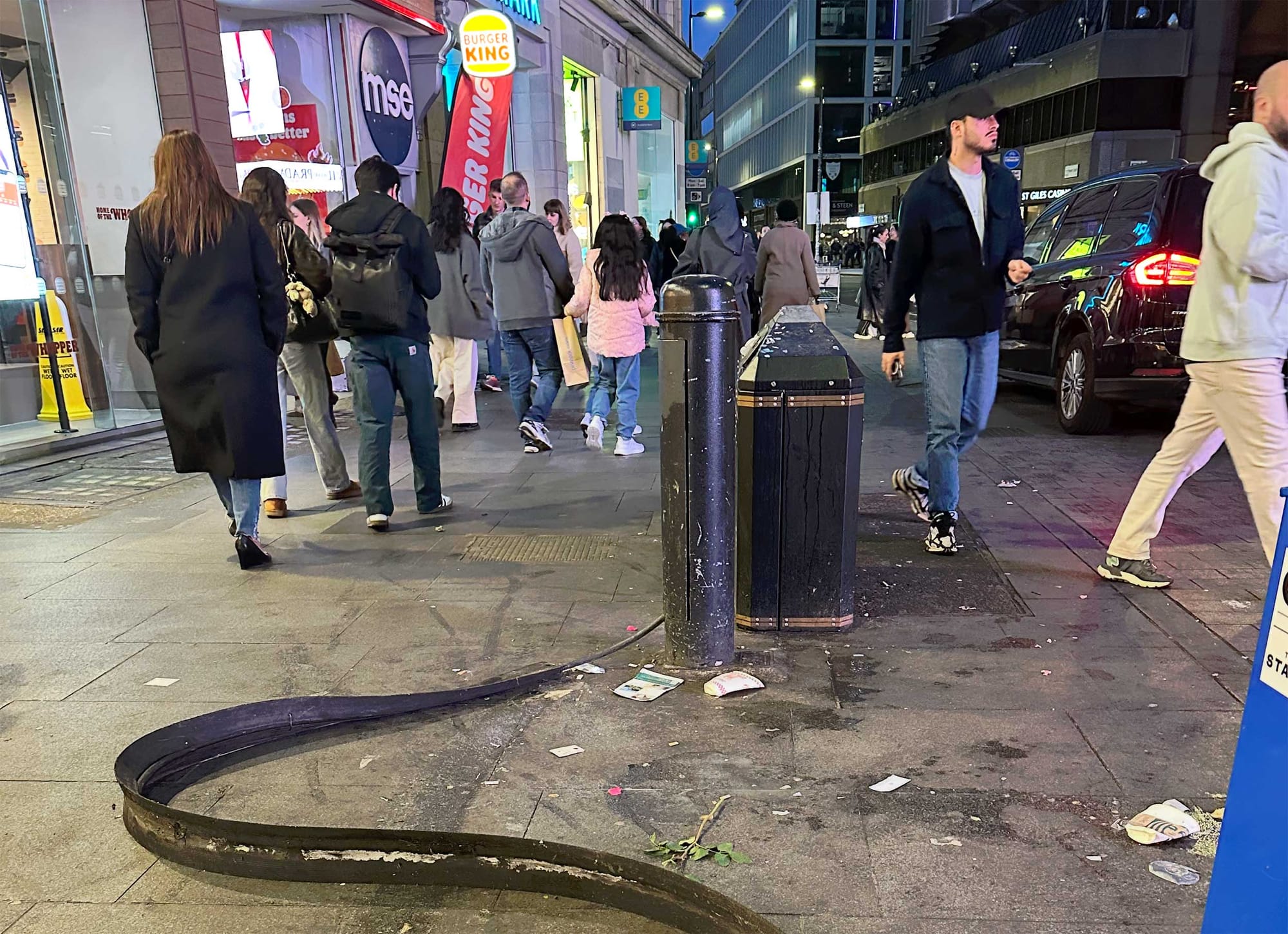A pedestrian power cable protector twisted and flipped upside down on a sidewalk.