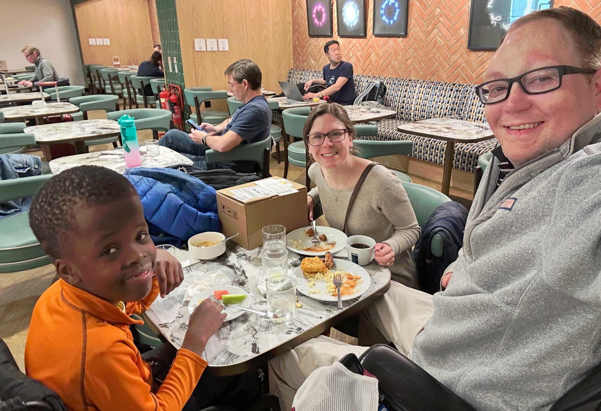 Selfie of John, Stevie and Robert seated at a table in the airport lounge.