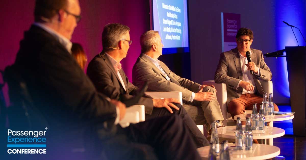 John seated in the near end of the stage, listening to the moderator.