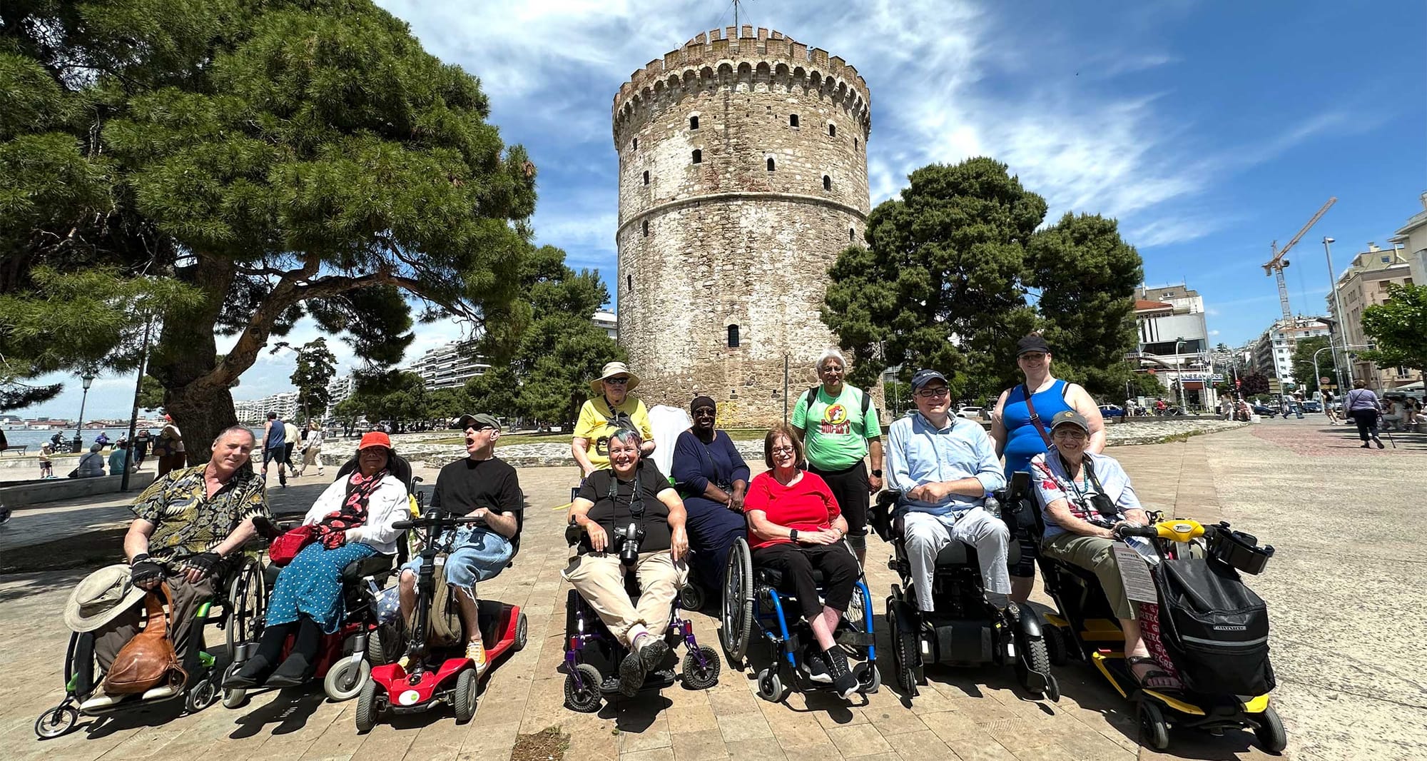 Group of wheelchair and scooter users in front of White Tower in Thessaloniki, Greece.