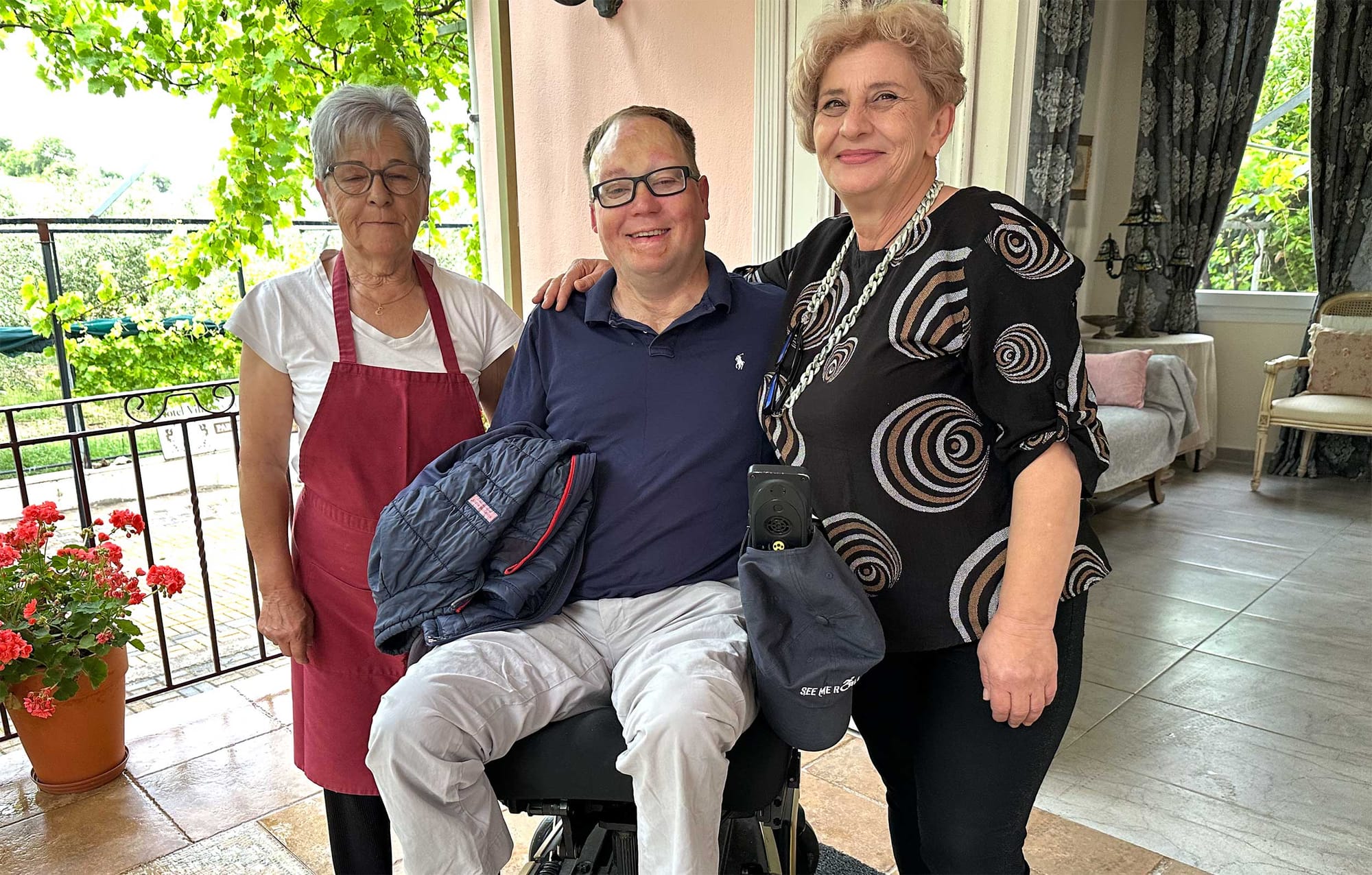 John pictured with two women in front of an authentic Greek hotel and villa.