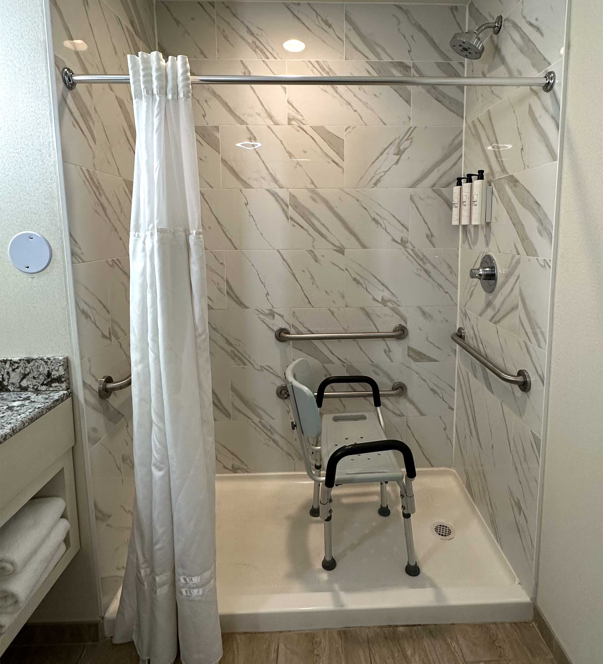 Shower with lip, portable shower seat and no handheld shower head.