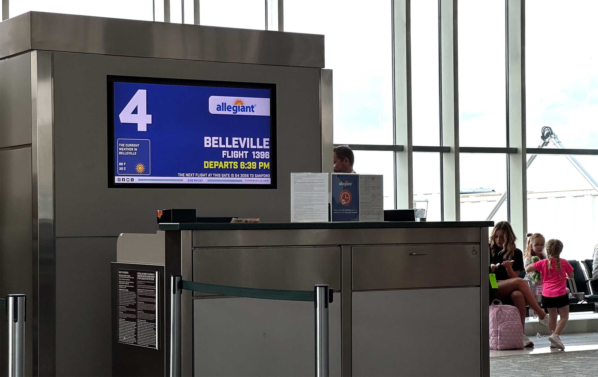 Boarding gate and departures board showing Allegiant flight to Belleville.