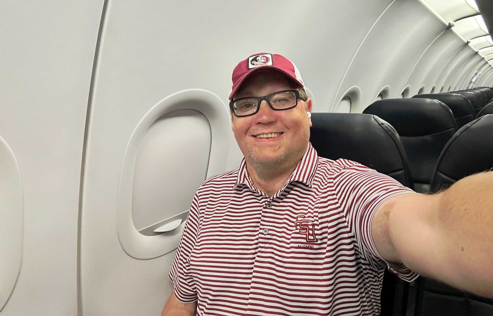 Selfie of John seated in window seat on Allegiant Air airplane.