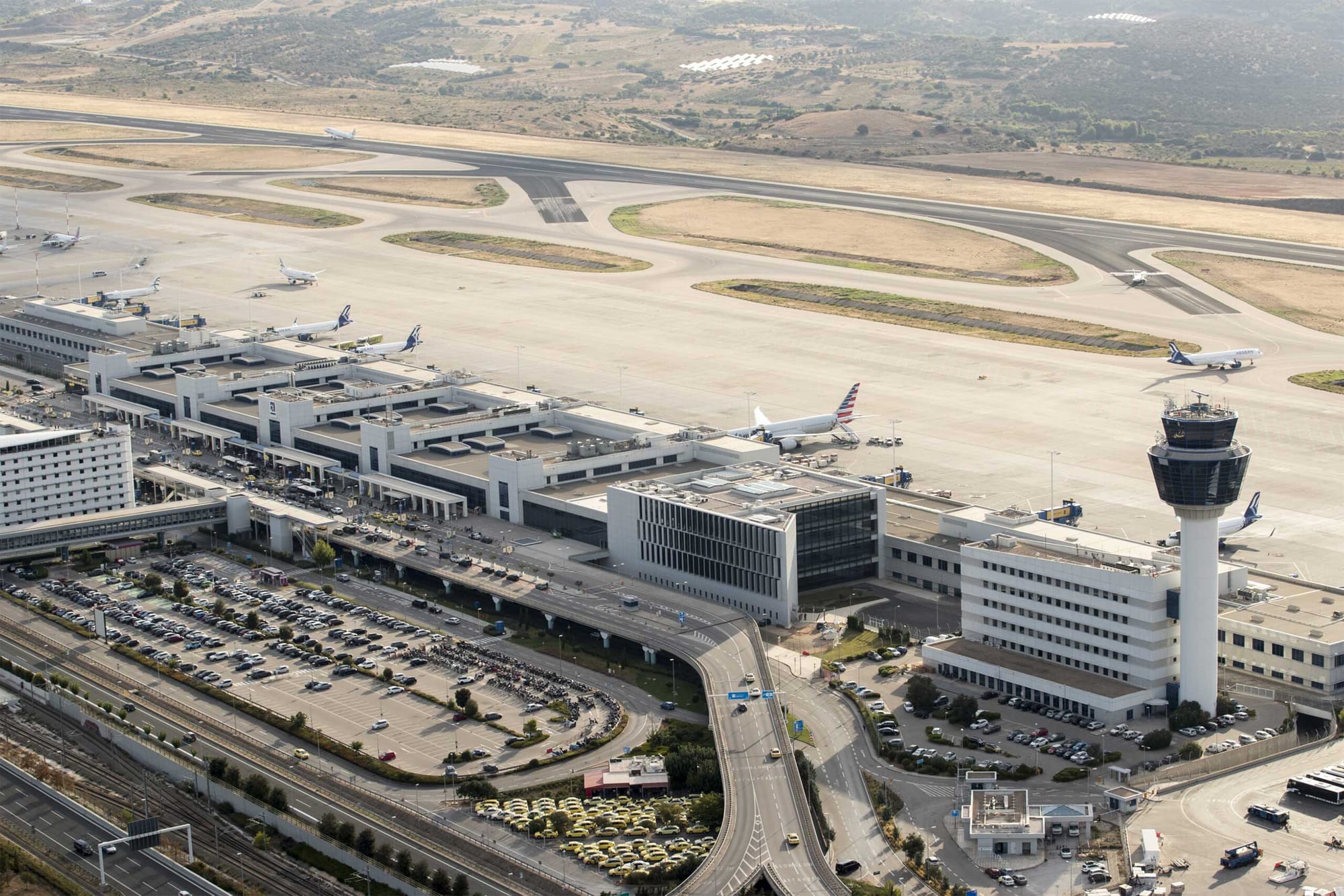 Aerial photo of Athens International Airport terminal building and airplanes on runway.