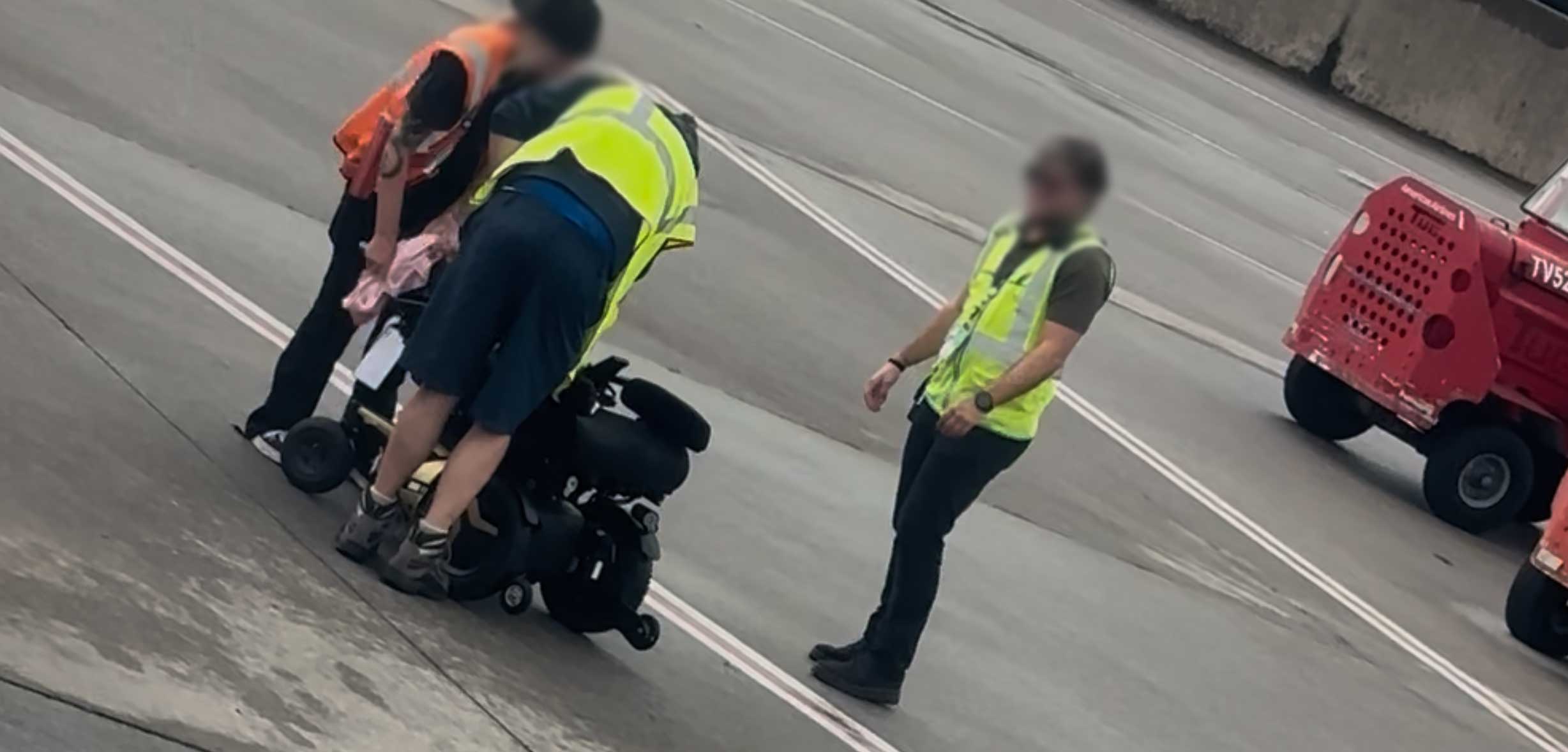 Airline staff drying off a wheelchair with a towel after unloading it from an airplane.