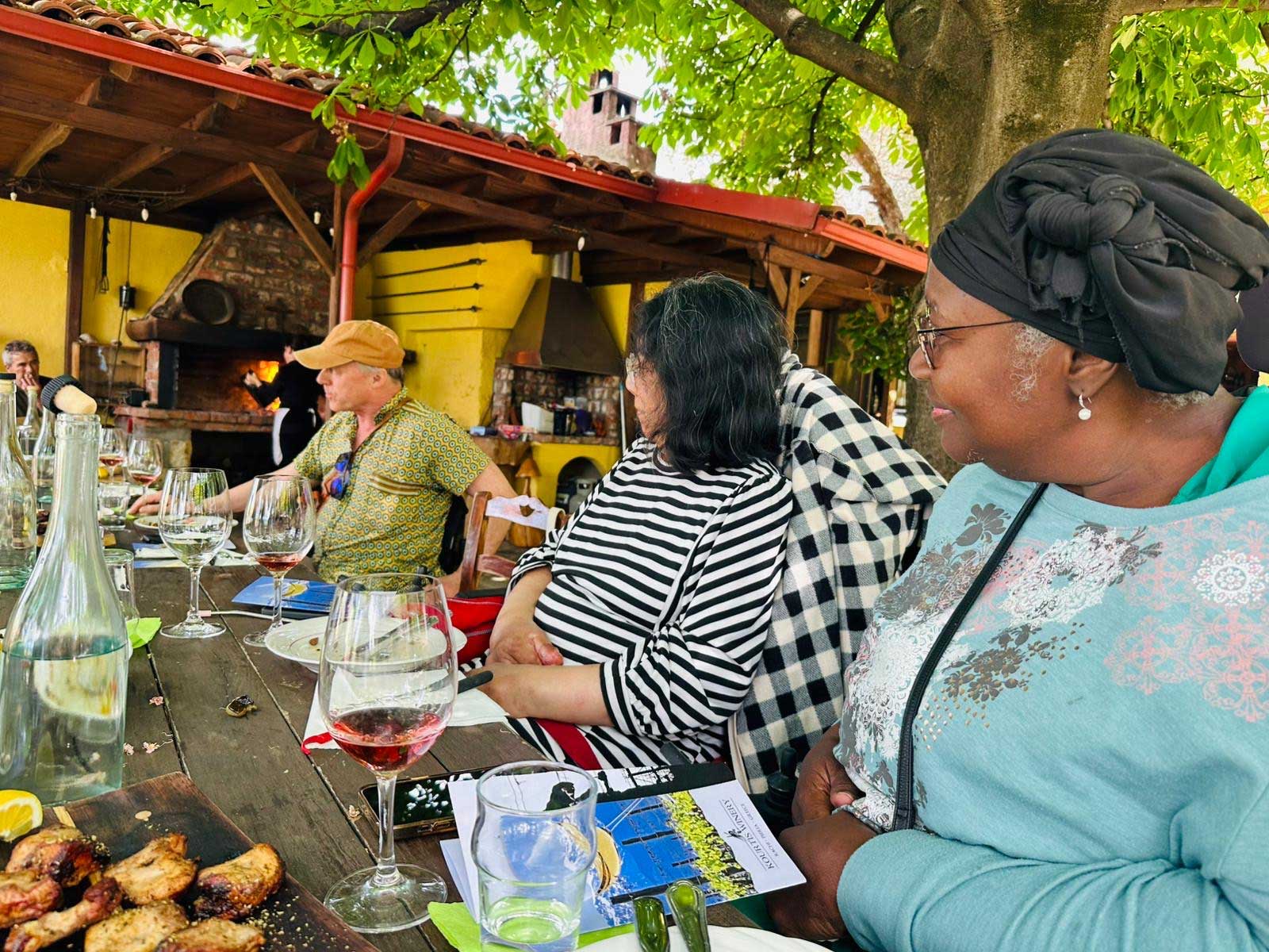Wheelchair users seated at a table eating and drinking wine.