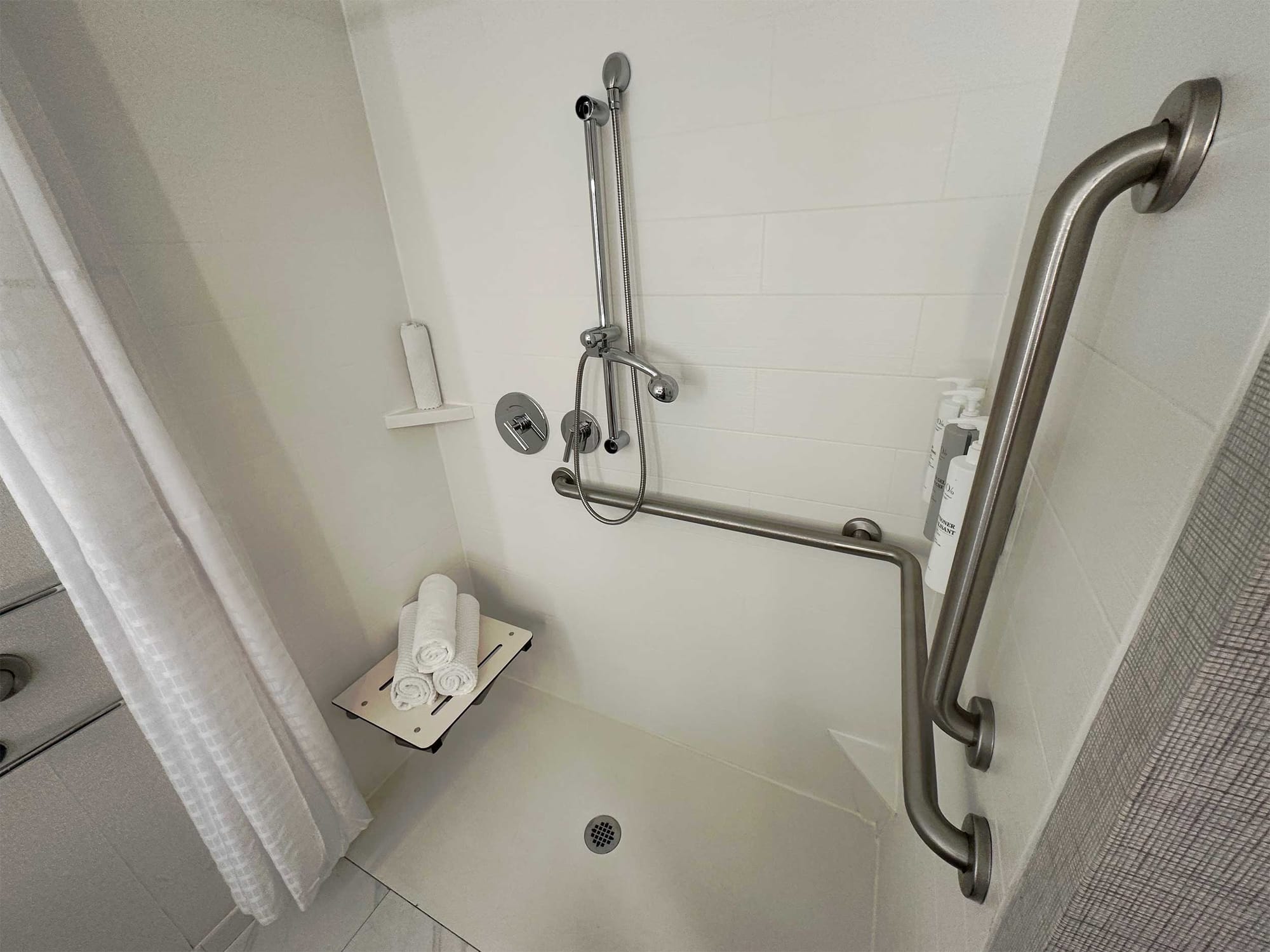 Roll-in shower with built-in seat and grab bars.
