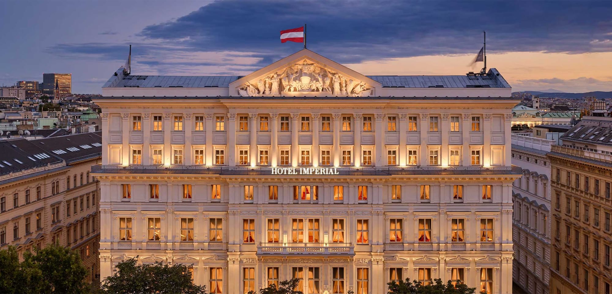 Exterior photo of regal palace turned hotel with the Austrian flag on the rooftop.