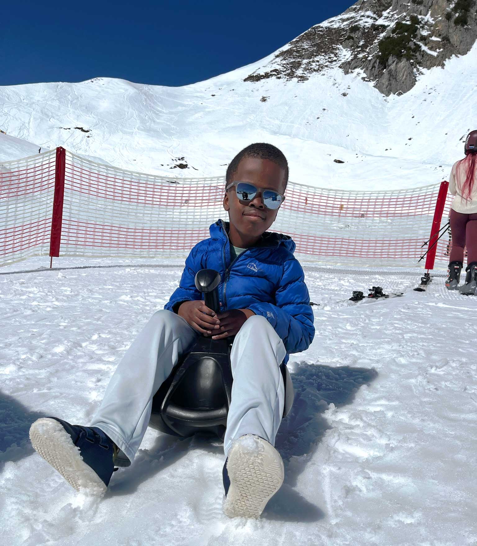Robert sitting on a sled in the snow on the mountainside.