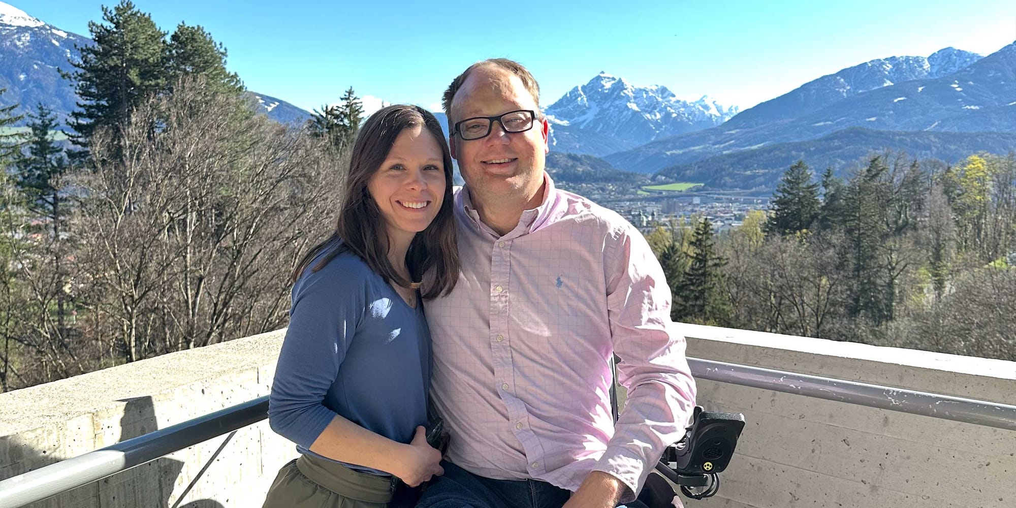 Stevie and John pictured in front of snow capped mountains in the distance.