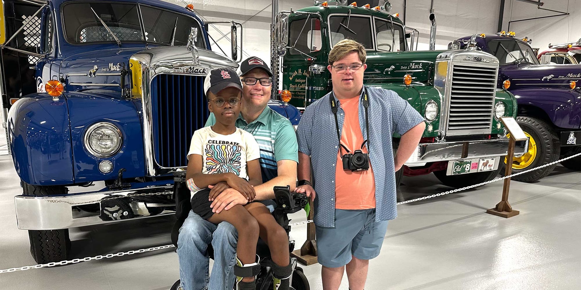 John and Robert with Houston from Downs and Towns posing in front of a series of Mack semi trucks.