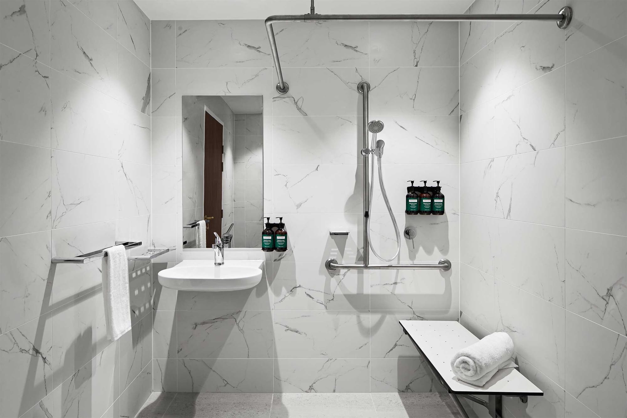 Accessible bathroom with roll-in shower, shower seat, roll-under sink and grab bars.