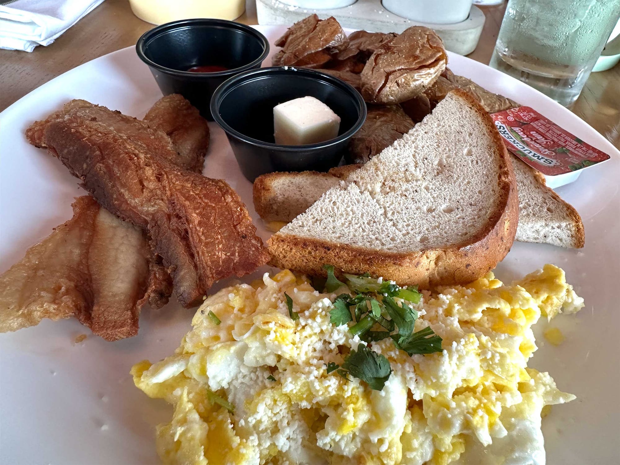 Breakfast of eggs, potatoes, bacon and toast.