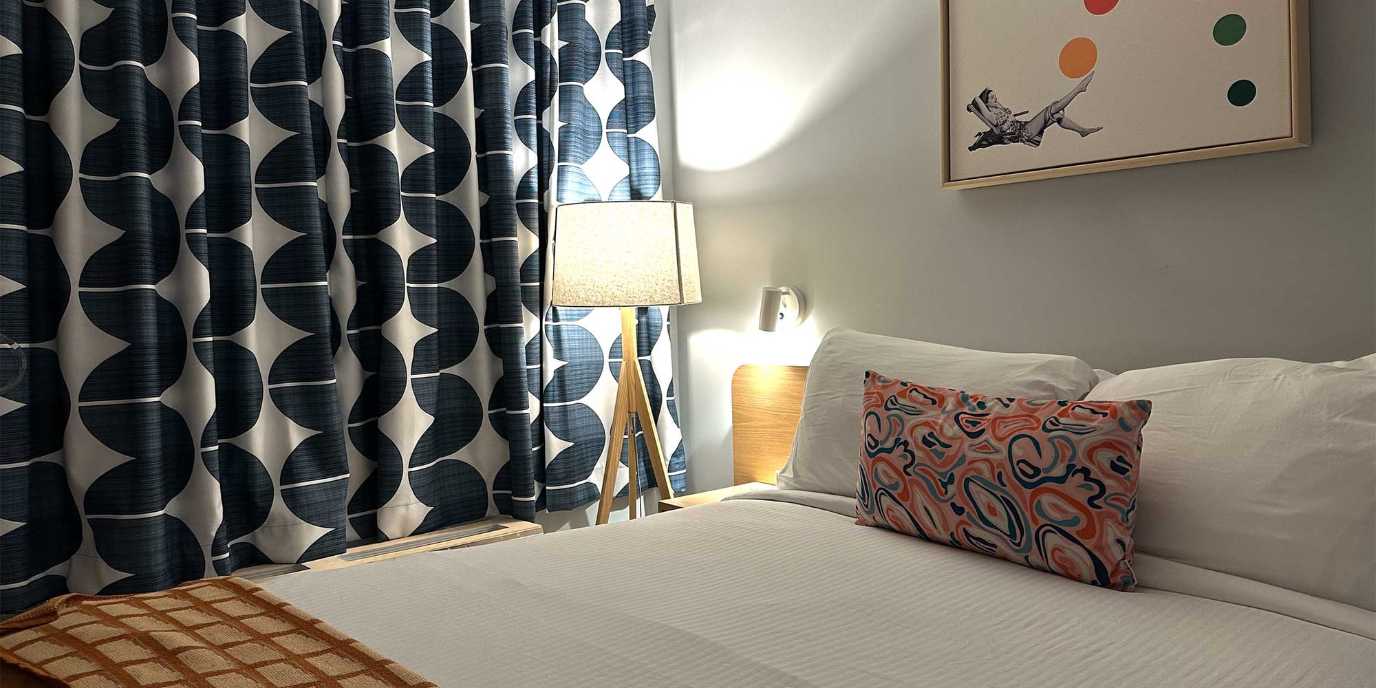 Close-up view of bed, curtains, lamp and artwork in motel room.