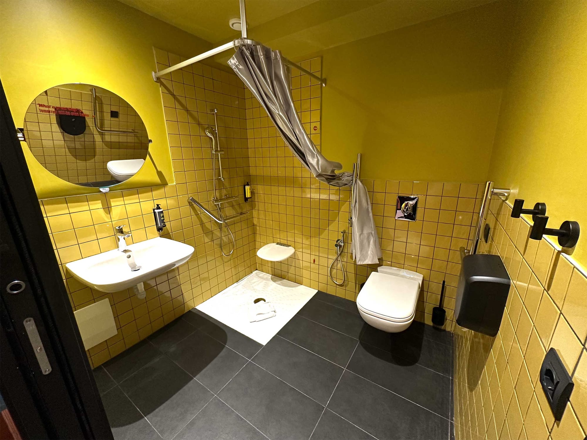 Toilet with grab bars, roll-in shower with built-in seat, and roll-under sink.